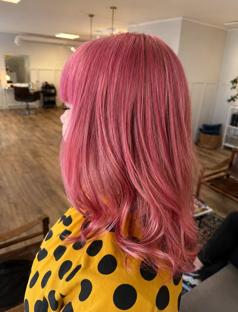 Intensiv rosa hårfärg med mjuka lockar utfört av Hair by Isabelle i Aneby.